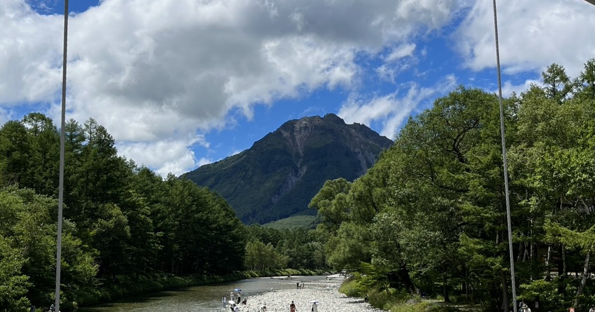 The clear Azusa River in Kamikochi leading to Yakedake volcano under a blue summer sky with visitors on the riverbank